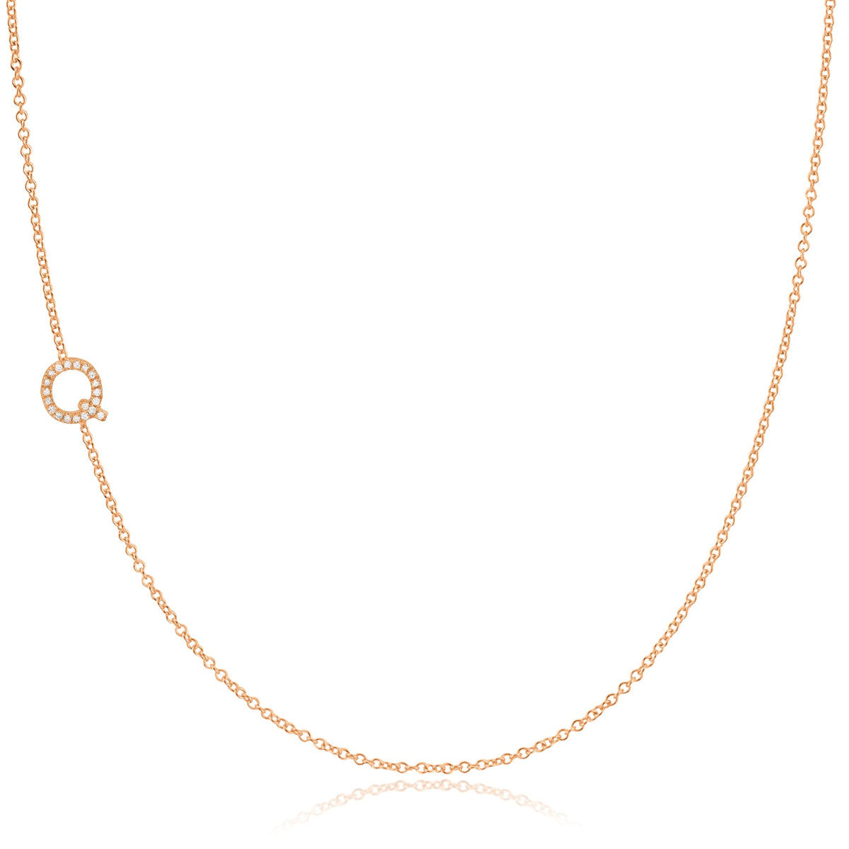 A rose gold necklace with a pave letter q charm on a white background. 