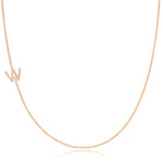 A rose gold necklace with a pave letter W charm on a white background. 