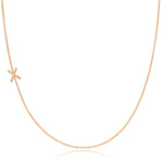 A rose gold necklace with a pave letter X charm on a white background. 