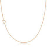 A rose gold necklace with a pave letter D charm on a white background. 