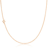 A rose gold necklace with a pave letter F charm on a white background. 