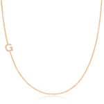 A rose gold necklace with a pave letter G charm on a white background. 