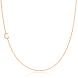 A rose gold necklace with a C letter pave charm on a white background. 