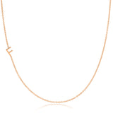 A rose gold necklace with a F letter charm on a white background. 