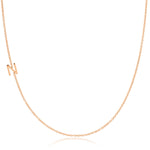 A rose gold necklace with an N letter charm on a white background. 