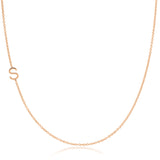 A rose gold necklace with an S letter charm on a white background. 