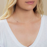 A close-up of a woman's neck wearing a 14k Gold Asymmetrical Number Necklace - 5 in rose gold, styled with blonde hair and a white top.