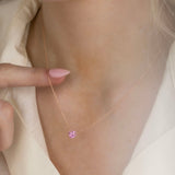 Close-up of a neck wearing The Sweetheart Necklace - Pink Sapphire in rose gold with a cream shirt.