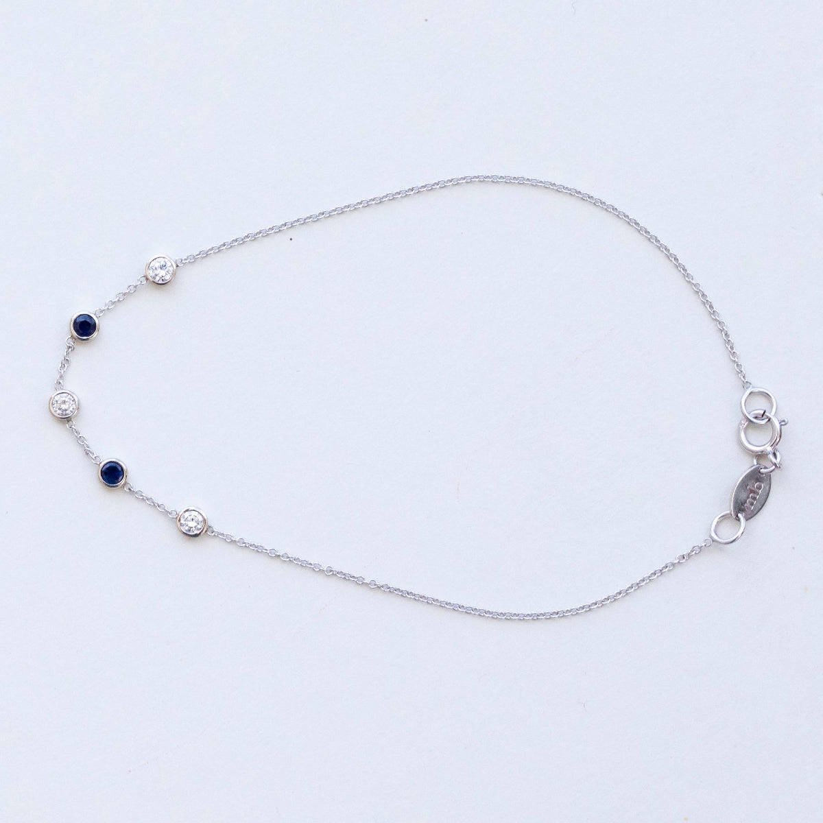 A white gold Custom Gold Bracelet – 5 Letters with five birthstones (three diamond and two sapphire) on a white background.