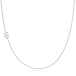 A white gold necklace with a E letter pave charm on a white background. 