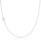 A white gold necklace with a E letter pave charm on a white background. 
