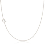 A white gold necklace with a G letter pave charm on a white background. 