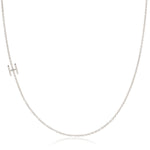 A white gold necklace with a H letter charm on a white background. 