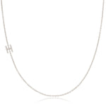 A white gold necklace with a H letter pave charm on a white background.
