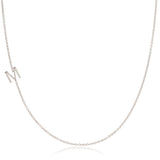 A white gold necklace with an M letter charm on a white background. 