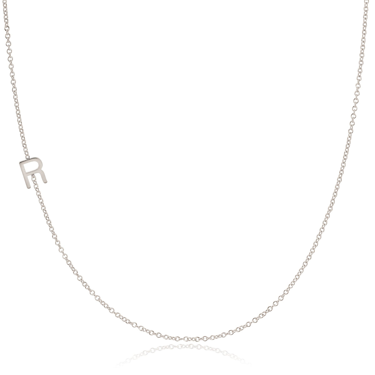 A white gold necklace with an R letter charm on a white background. 