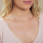 A close-up of a woman's neck wearing a white gold necklace with a letter Z charm.