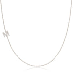 A white gold necklace with a letter M pave charm on a white background.