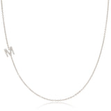 A white gold necklace with a letter M pave charm on a white background.