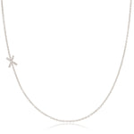 A white gold necklace with a letter X pave charm on a white background.