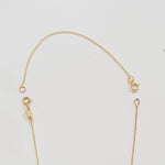 A yellow gold chain extender shown on top of a partially visible yellow gold cable-chain necklace on a light grey background.