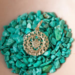 The Zodiac Necklace - Cancer pendant laid on top of turquoise stones. 