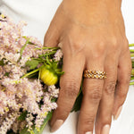 A hand wearing two The Daisy Bouquet Rings and holding a bunch of flowers. 