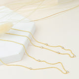 A Triple Diamond Layering Necklace and a Quintet Diamond Layering Necklace in yellow gold laid on a white and nude coloured surface.