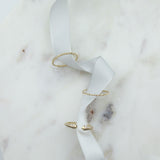 A Pave Diamond Ring, 4 Diamond Ring and Open Diamond Ring on white ribbon against a white marble background.