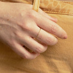 Close-up of a hand wearing a 4 Diamond Ring, holding onto yellow denim pants.