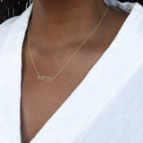A close-up of a décolletage wearing a Justice Necklace and a white linen top. 
