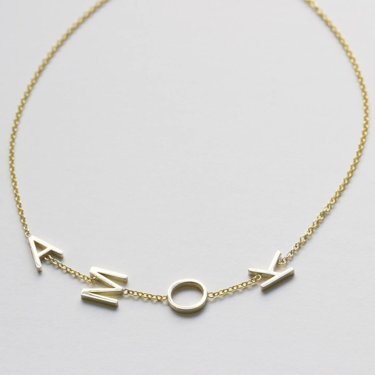 A yellow gold Custom Gold Bracelet – 4 Letters with the letters A, M, O and K on a white background.