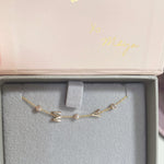 A yellow gold Custom Gold Bracelet – 5 Letters – with the letters M and A and three diamond birthstones, in a Maya Brenner jewellery box.