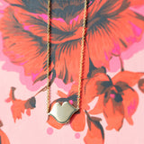 A Lip Pendant necklace on a red and pink floral background. 