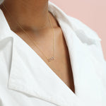 A LOVE Necklace in yellow gold on a cable chain on a white background. 