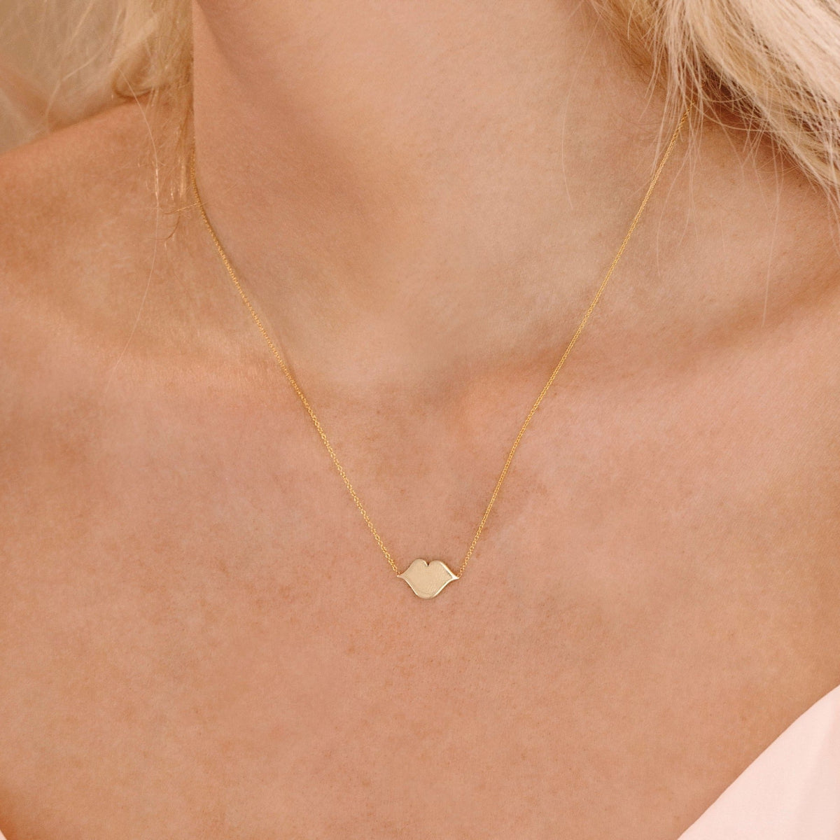 A close-up of a blonde woman's neck wearing a  Lip Pendant necklace. 