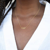 Close-up of a decellotage wearing a RiseUp Necklace with a white top. 