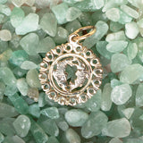 The Zodiac Necklace - Pisces pendant laid on top of small green crystal stones. 