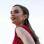 Lily Collins wearing a yellow gold Solid Eclipse Earring - Large with a red top and red lipstick against a white background.
