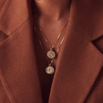 Close-up of a décolletage wearing several Zodiac Necklaces with a brown blazer jacket. 