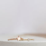 A rose gold Twinkle Twinkle Ring and yellow gold Birthstone Ring (Diamond) against a light grey blurred background.
