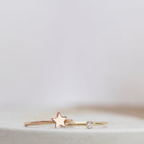 A rose gold Twinkle Twinkle Ring and yellow gold Birthstone Ring (Diamond) against a light grey blurred background.
