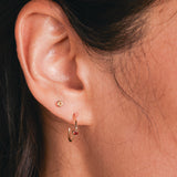 Close-up of a Birthstone Stud - Citrine (November) and Birthstone Hoop - Garnet (January) in a woman's ear. 