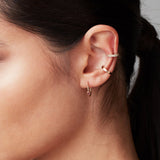 Close-up a yellow gold Birthstone Hoop in Pink Tourmaline - October, Rectangle Ear Cuff and Pave Double Ear Cuff in a woman's ear with her black hair in a ponytail. 