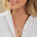 Close-up of a blonde woman wearing a Zodiac Necklace - Cancer with a white shirt against a neutral background. 