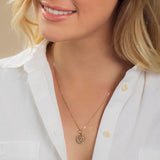 Close-up of a blonde woman wearing a Zodiac Necklace - Cancer with a white shirt against a neutral background. 