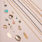 A Box Chain, Black Rhodium Antique Bead Chain, Oval Link Chain, Round Curb Chain,  Opal Dangle Charm, Small Abalone Cabochon Charm, Turquoise Heart Charm,
Cut Out Heart Charm, Diamond Heart Locket Charm, Abalone Leaf Charm, Turquoise Dangle Charm, Pink Opal Tear Drop Charm, Onyx Dangle Charm, Engraved Heart Charm, Heart Locket Charm, two Balance Crystal Charms, Moonstone Crescent Charm, 20th Anniversary Leaf Pendant and a Large Abalone Cabochon Charm against a light pink background. 