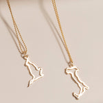 An England Necklace and an Italy Necklace laid on a cream surface against a light brown background.