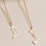 An England Necklace and an Italy Necklace laid on a cream surface against a light brown background.