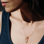 Close-up of a woman's décolletage wearing The Clarity Retreat Necklace, styled in a navy tank top.